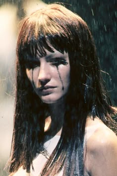 a woman with long hair and piercings on her face is standing in the rain