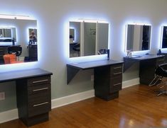 three desks with mirrors and lights on them