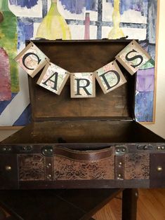 an old trunk with letters that spell out the word cards in front of a painting