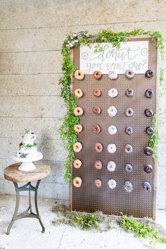 a doughnut display on a wall next to a table with a cake and cupcakes