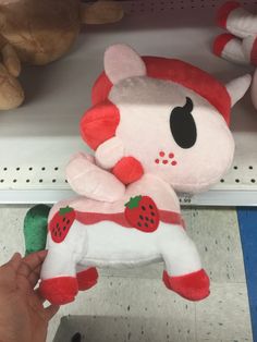 a person is holding a stuffed animal that looks like a cat with strawberrys on it