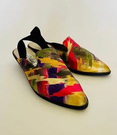 Stunning 80s New Wave 'Miss Millie' metallic leather multi-colored sling back flats. Geo paint splatter design in pinks, greens, purples, silvers, pewters and yellows. Black elastic sling back and black soles. Made in New York by MBC Originals. Length: 10 1/2 inches Across ball: 3 1/2 inches Multicolor Slip-on Mules For Spring, Multicolor Closed Toe Mules For Spring, Spring Multicolor Closed Toe Mules, Spring Multicolor Leather Mules, Multicolor Pointed Toe Mules For Summer, 1980s New Wave, Sling Back Flats, 80s New Wave, Sling Back Shoes