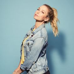 a woman with her hair in a ponytail wearing a jean jacket and black leggings