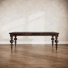 a wooden table sitting on top of a hard wood floor next to a white wall