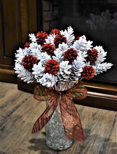 a glass vase filled with white and red flowers on top of a wooden table next to a fireplace