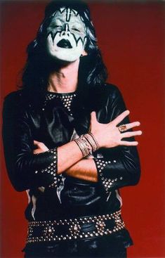 a man with his arms crossed wearing a black leather jacket and white face paint on