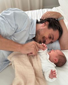 a man laying on top of a bed next to a baby