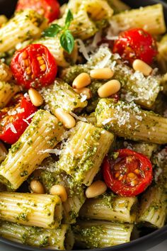 pasta with pesto, tomatoes and pine nuts in a black bowl