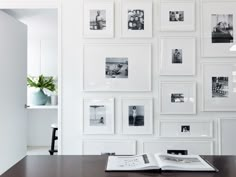 an open book sitting on top of a wooden table next to a wall covered in pictures