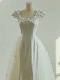 a white dress with flowers on the shoulders and shoulder, sitting on a mannequin