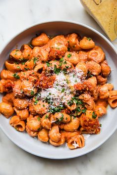 a white plate topped with pasta covered in sauce and parmesan cheese