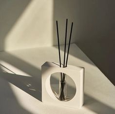 a vase with sticks in it sitting on a white counter top next to a window