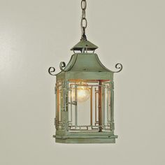 an old fashioned lantern hanging from a chain on a wall with light bulb in the center