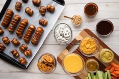 an assortment of pretzels, carrots, celery and dips on a tray