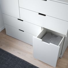 an open drawer in the middle of a white dresser