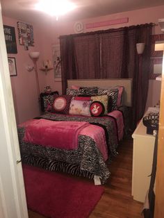 a bed room with two beds covered in pink and zebra print blankets on top of it