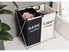 a black and white laundry hamper next to a bathtub with plants in it