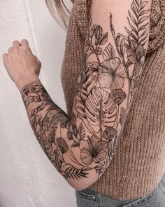 a woman's arm with flowers and leaves on it