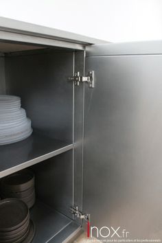 the inside of a metal cabinet with plates stacked on top of each other in front of it