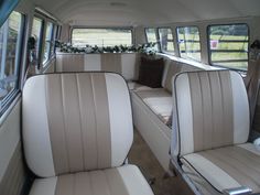 the interior of an old bus with white and tan leather seats in front of two windows