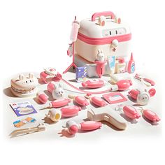 an assortment of toys including a suitcase and other items on a white surface with pink trimmings