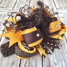 "For just a hint of playfulness and plenty of sparkle, this brown and mustard girl's hair bow is simply fall-tastic! Handcrafted with your lil' pumpkin in mind, it features a burst of gold and brown patterned ribbons with rhinestones and fluffy chocolate feathers to top it off in style. Set on your choice of alligator hair clip, french barrette or a stretch headband according to the age of your little girl. It also makes a fun gift idea to herald in the autumn season! It is an original Beautiful Brown And Yellow Hair, Thanksgiving Hair Bows, Baby Hair Bows Headbands, Handmade Baby Headbands, Thanksgiving Hair, Holiday Hair Bows, Stacked Hair Bow, Fall Headbands, Hair Bows For Girls