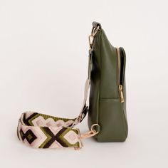 a green handbag with a pink and white pattern on the strap next to it