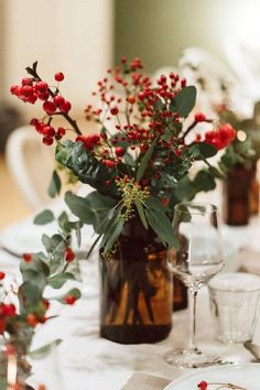 the table is set with red berries and greenery