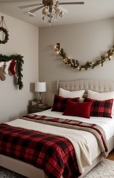 a bedroom decorated for christmas with red and black plaid bedding, wreaths and stockings on the wall