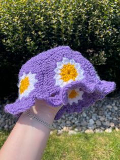 Violet crochet bucket hat with flowers all around the circumference as well as on the top! it has a wavy brim as well! Spring Beach Crochet Hat With Flower Shape, Handmade Whimsical Bucket Hat For Spring, Whimsical Handmade Bucket Hat For Spring, Crochet Mini Bucket Hat For Spring, Spring Crochet Mini Bucket Hat, Handmade Purple Crochet Hat For Spring, Purple Crochet Hat For Spring, Spring Crochet Cloche Hat In One Size, Cute Flower Hat For Beach