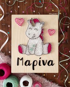 a wooden sign that says mapia with a unicorn on it and some yarn next to it