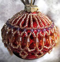 a red ornament hanging from a metal hook on a marble surface with beads