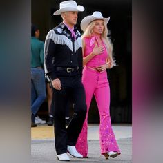 a man and woman in cowboy hats walking down the street