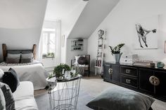 an attic bedroom with white walls and gray carpeted flooring is furnished with black furniture