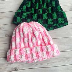 two knitted hats sitting on top of a wooden floor