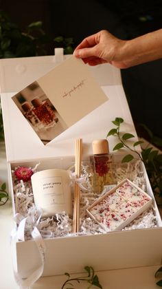 a person holding a card in a white box with flowers and candles on the table