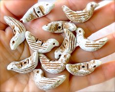 small ceramic birds sitting in the palm of someone's hand with white paint on them