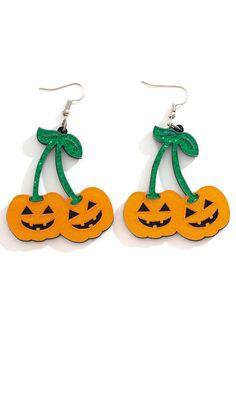 two pumpkins with green leaves on them are hanging from the ear wires, and one is