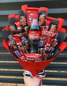 someone is holding a bouquet of chocolates and candy bars in their hand with a coca - cola bottle as the centerpiece