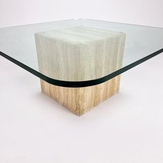 a glass and wood coffee table with an interesting design on it's base, in the shape of a cube