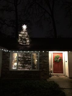 a lighted christmas tree in front of a house