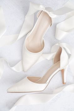 a pair of white high heels with satin ribbons around them