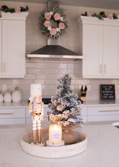 a christmas tree on a tray in the middle of a kitchen with candles and decorations