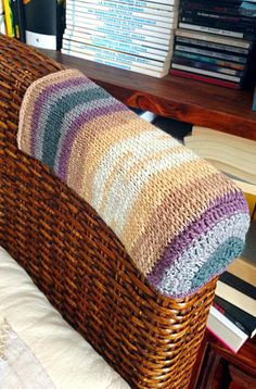 a wicker bed with a pillow on top of it next to a bookshelf