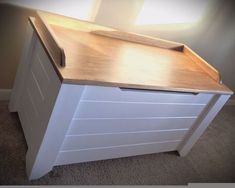 a white dresser with wooden top in a room next to a wall and carpeted floor