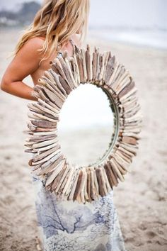 a woman holding a mirror made out of driftwood