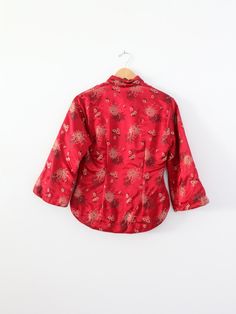 "This is a vintage Chinese silk padded jacket. Rich red satin brocade shapes the women's jacket with a black, cream, and gold floral pattern. The coat is padded and features a rounded collar, three-quarter sleeves, and a side closure with ribbon buttons. ○ red satin brocade coat ○ black, cream, and gold floral pattern ○ double, padded coat ○ side closure ribbon buttons ○ rounded collar ○ three quarter sleeves CONDITION In great condition. Approximate fit: Small MEASUREMENTS Bust: 34\" Length: 24 Brocade Shirt, Chinese Jacket, Hippie Boots, Padded Coat, Red Satin, Gold Floral, Cream And Gold, Cheongsam, Padded Jacket