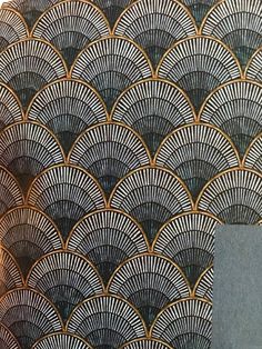 an intricately designed wallpaper with gold and black designs on the back, along with a gray background