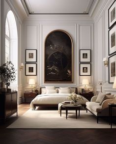 an elegant bedroom with white walls and wood flooring, framed pictures on the wall