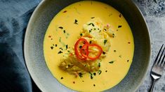 a bowl filled with soup and garnished with red bell peppers, on top of a blue napkin